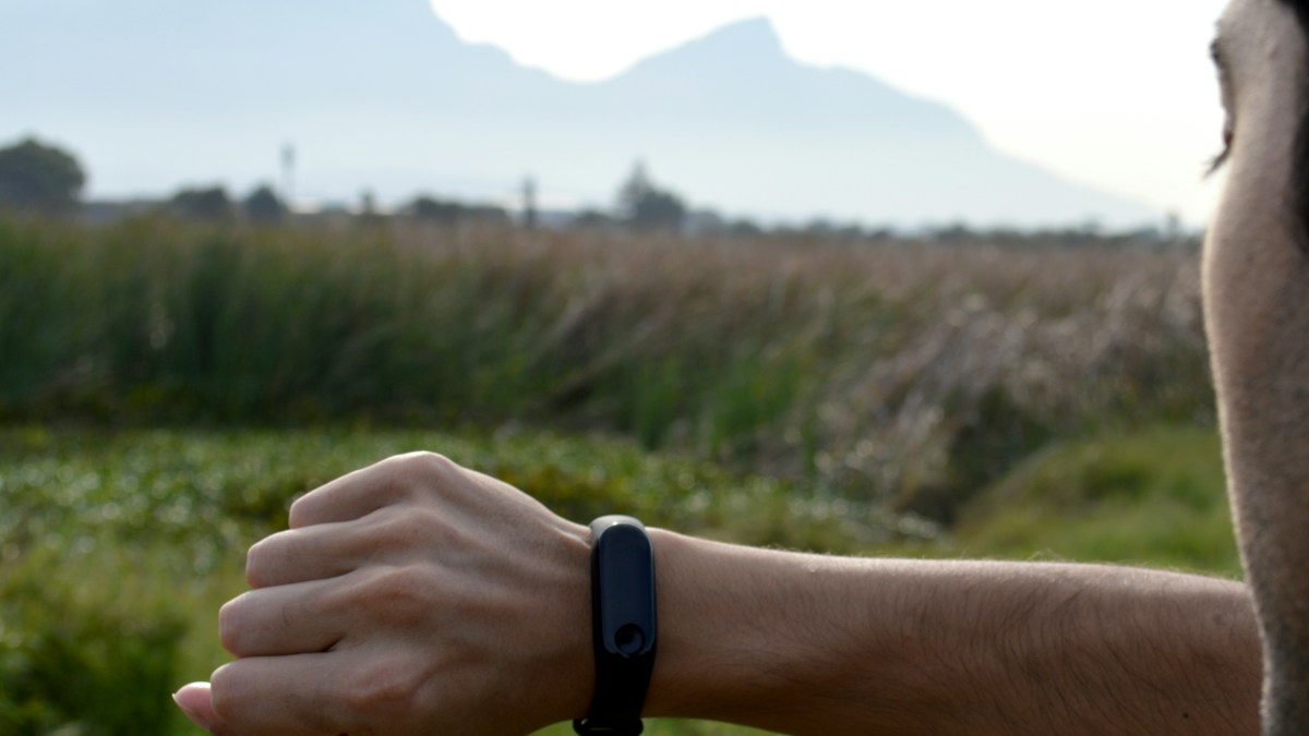Runner checking a black fitness tracker on their wrist outdoors