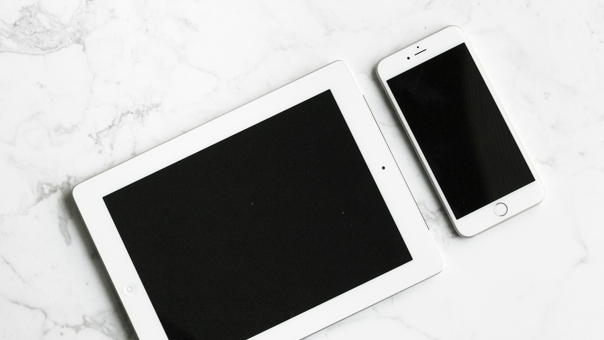 Tablet and smartphone arranged beside a laptop on a desk